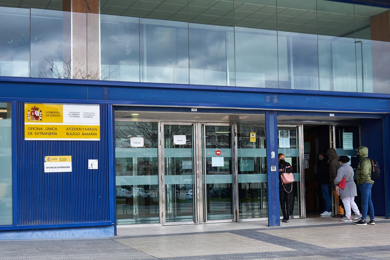 People entering the immigration office in Pamplona, symbolizing the impact of the Spain migrant regularization program.