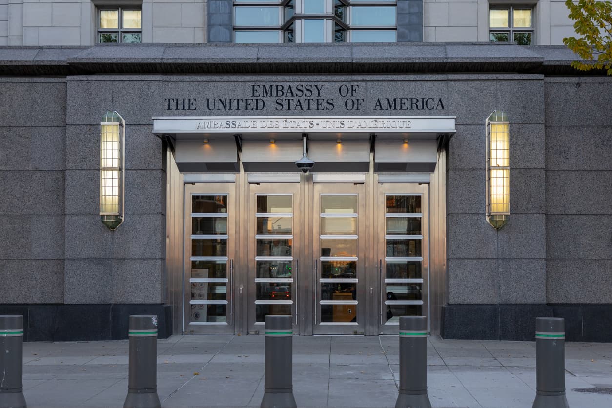 Entrance to a US embassy with bilingual English and French signage reading Embassy of the United States of America, where US citizenship renunciations are processed
