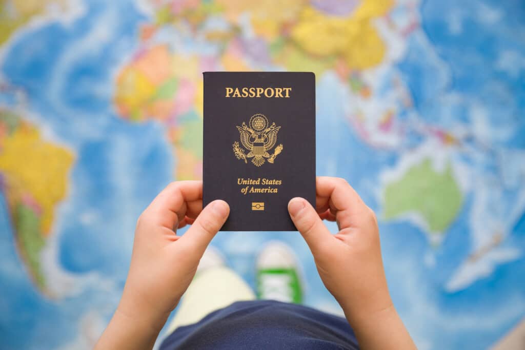 Hands holding an American passport in front of an enlarged globe, representing the desire to move to Utaly.