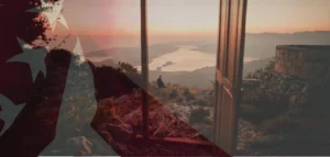 Open door to new horizons at sunset overlooking mountains and a serene bay — symbolizing opportunities for American emigration and a fresh start abroad.