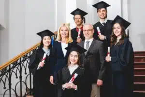 smiling-students-in-graduation-caps-holding-diploma