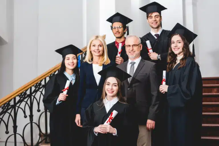 smiling-students-in-graduation-caps-holding-diploma