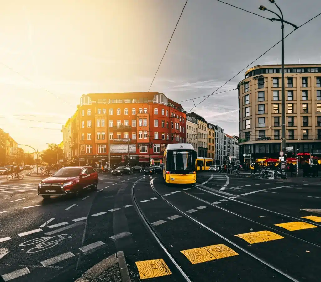 Transgender Healthcare in Europe: The Best Places for Gender-Affirming Care 5 A busy street in Berlin, Germany, at sunset. A bright yellow tram is in the foreground, moving along tracks as cars and cyclists travel around.