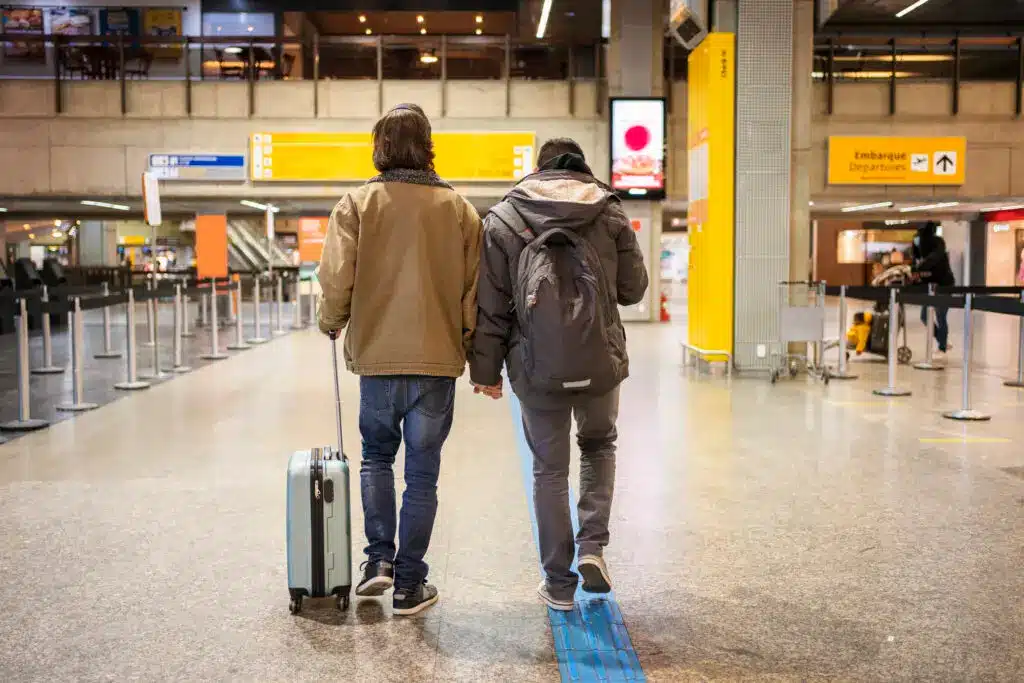 LGBTQIA+ Americans Claiming EU Citizenship by Ancestry 2 A couple travels through an airport, representing LGBTQIA+ growing interest in moving abroad and EU citizenship by ancestry.