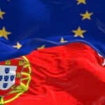 Close-up of Portugal and the European Union flags waving on a clear day. Symbolizing Portugal's place among the top European digital nomad visas.