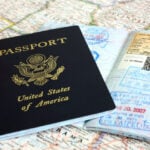 A US passport rests on an open passport showing entry stamps from Japan and Taiwan, reflecting the US passport decline now reshaping American travel access