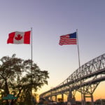 Canadian and American flags flying beside the Blue Water Bridge at the Canada-US land border, where US asylum claims in Canada are filed at official ports of entry.