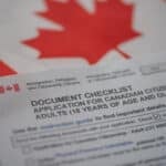 Document check list application for canadian citizenship next to Canadian flag, close up view.