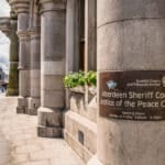 Aberdeen Sheriff Court sign on a granite courthouse column in Aberdeen, Scotland, the city where the racial harassment tribunal case was heard